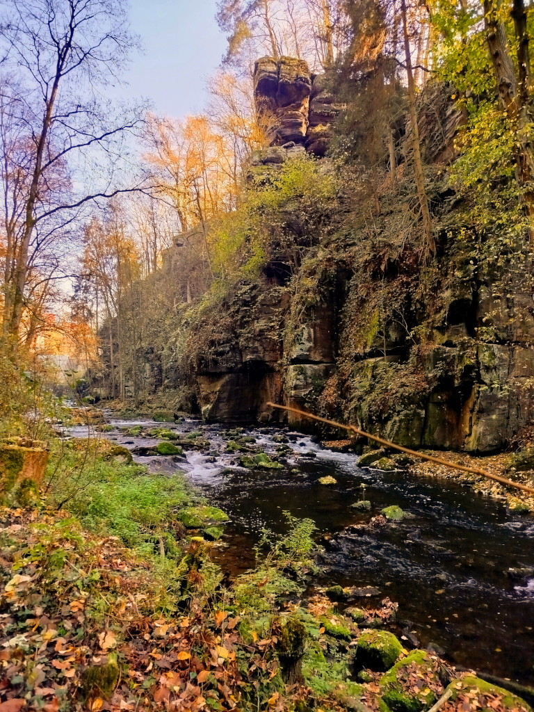 Skalna ściana nad rzeką w jesiennych barwach